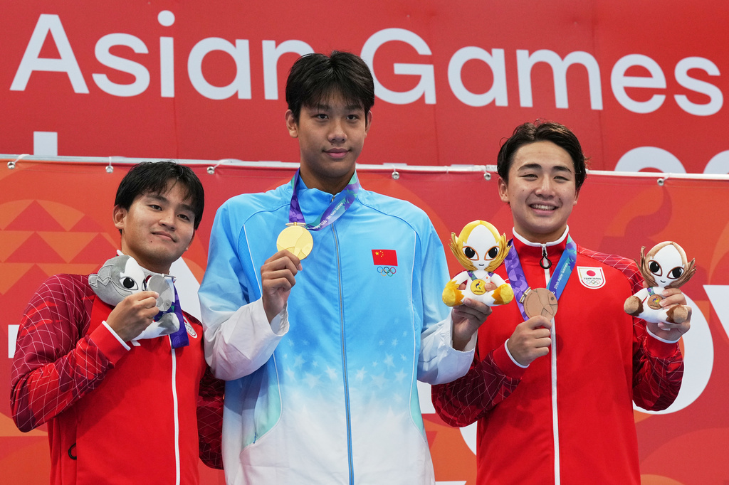 Gold medalist Zhang Zhanshuo of China, center, flanked by silver medalist Kaito Tabuchi of Japan, left, and bronze medalist Kazushi Imafuku of Japan pose on the podium after the men's 1500-meter freestyle final in swimming at the Asian Games in Tokyo, Sept. 22, 2026. (AP Photo/Hiro Komae)