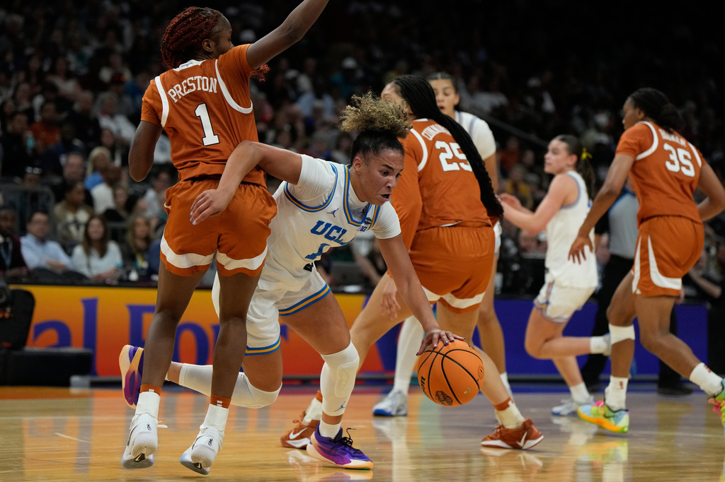 UCLA guard Kiki Rice (1) drives against Texas guard Bryanna Preston, left, during the first half of a women's NCAA college basketball tournament semifinal game at the Final Four, Friday, April 3, 2026, in Phoenix. (AP Photo/Ross D. Franklin)