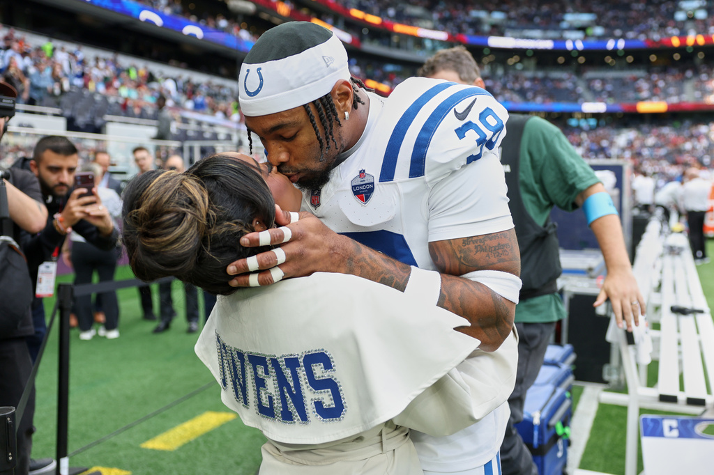 Simone Biles, multiple Olympic and World champion gymnast, kisses her husband Indianapolis Colts safety Jonathan Owens (38) on the side of the field before an NFL football game between Indianapolis Colts and Washington Commanders in London, Sunday, Oct. 4, 2026. (AP Photo/Ian Walton)
