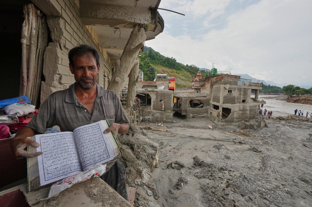 A resident shows a holy book as he salvages his belongings from damaged home filled with mud and debris in Devighat, in Nepal's Nuwakot district, Saturday, Aug. 29, 2026, following the Aug. 26 flash floods. (AP Photo/Rajesh Kumar Singh)