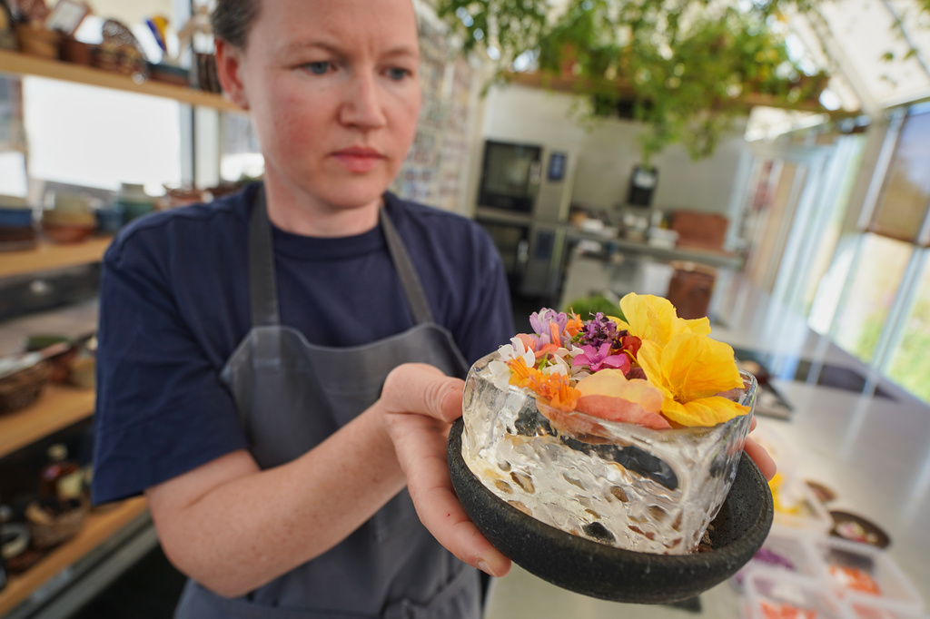 Noma's head of R&D Mette Brink Soberg holds a new berry gazpacho dish topped with flower petals in fine-dining restaurant Noma's test kitchen in Copenhagen, Denmark Tuesday, July 28, 2026. (AP Photo/James Brooks)