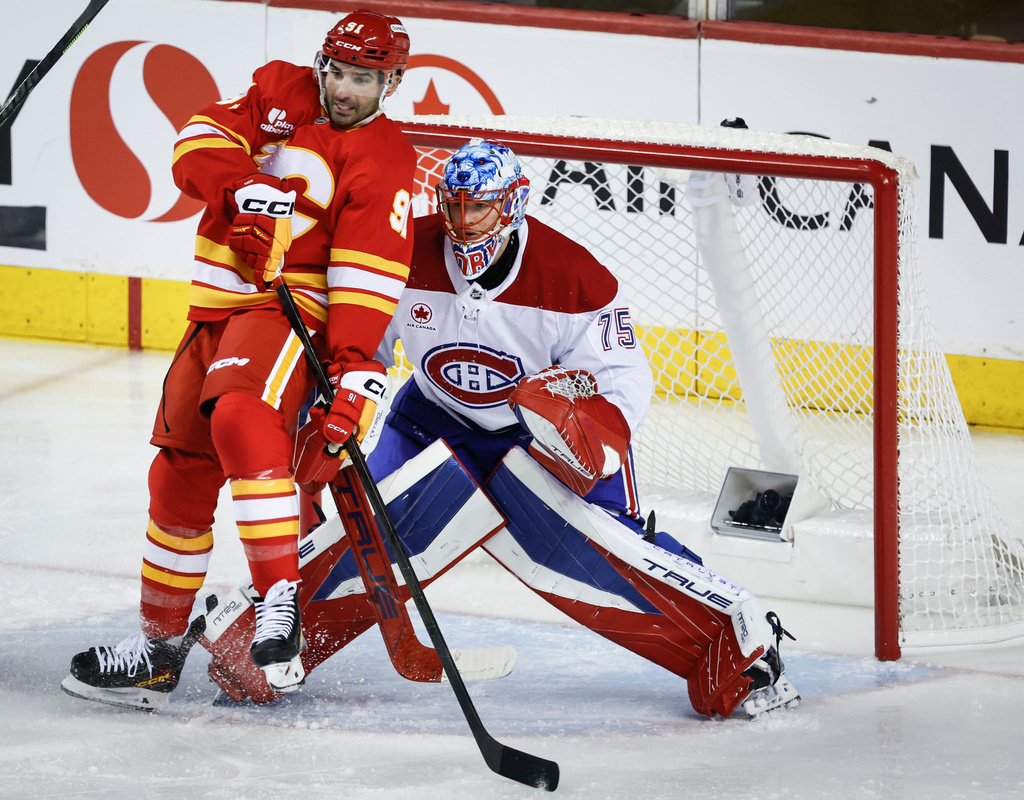 Montreal Canadiens goalie Jakub Dobes, right, holds his ground as Calgary Flames' Nazem Kadri is checked into him during second period NHL hockey action in Calgary on Wednesday, Oct. 22, 2025. (Jeff McIntosh/The Canadian Press via AP)