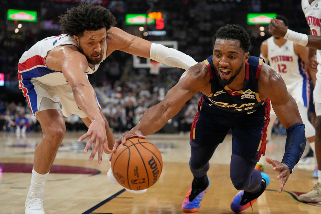 Detroit Pistons' Cade Cunningham, left, and Cleveland Cavaliers' Donovan Mitchell, right, reach for the ball in the first half of Game 4 of a second-round NBA basketball playoff series Monday, May 11, 2026, in Cleveland. (AP Photo/Sue Ogrocki)
