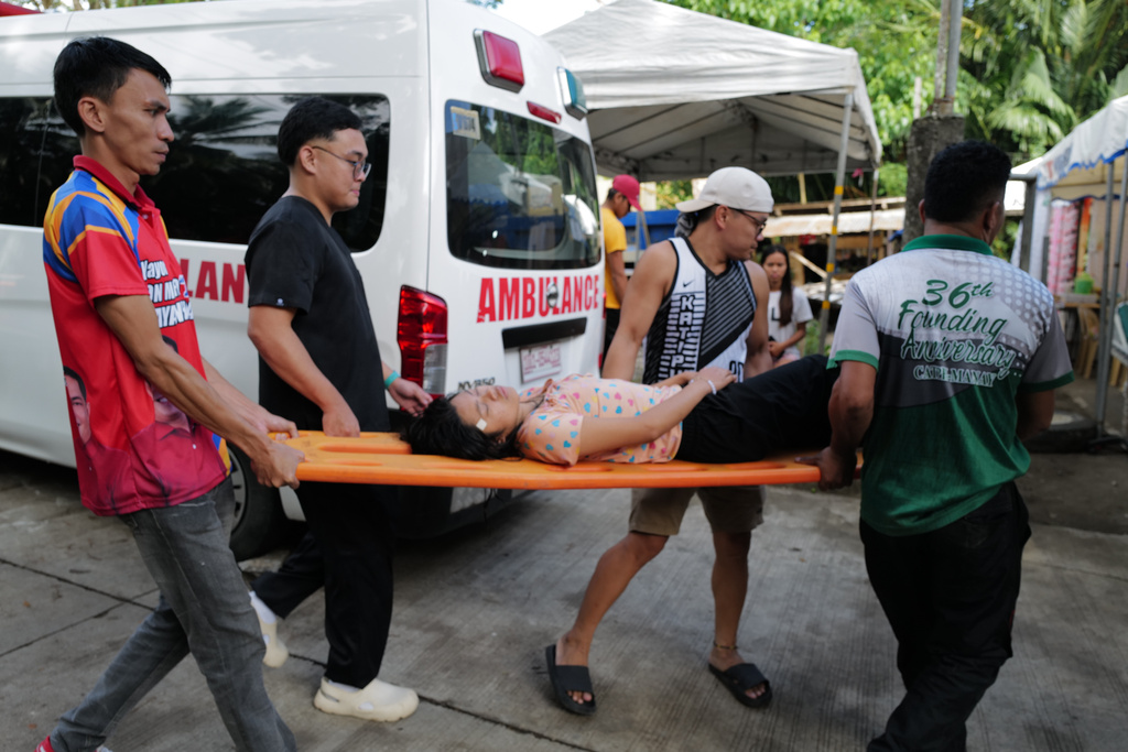 Residents carry a woman on a stretcher at the earthquake-hit Manay town, Davao Oriental province, southern Philippines Saturday, Oct. 11, 2025. (AP Photo/Jeoffrey Maitem)