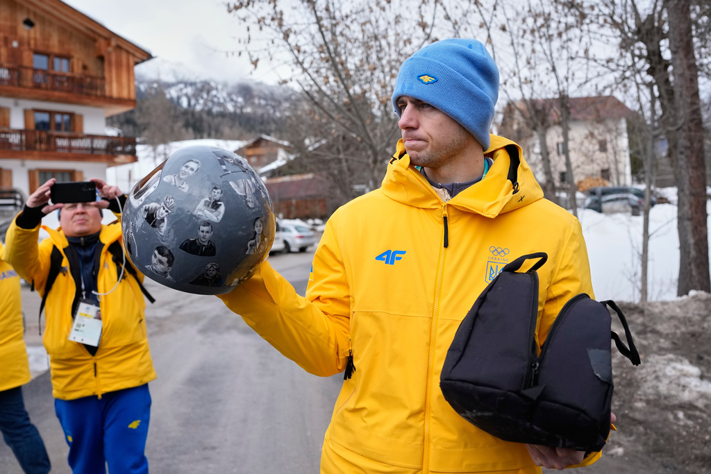 Ukrainian skeleton athlete Vladyslav Heraskevych holds his crash helmet as he stands outside the sliding center at the 2026 Winter Olympics, in Cortina d'Ampezzo, Italy, Thursday, Feb. 12, 2026. (AP Photo/Alessandra Tarantino)