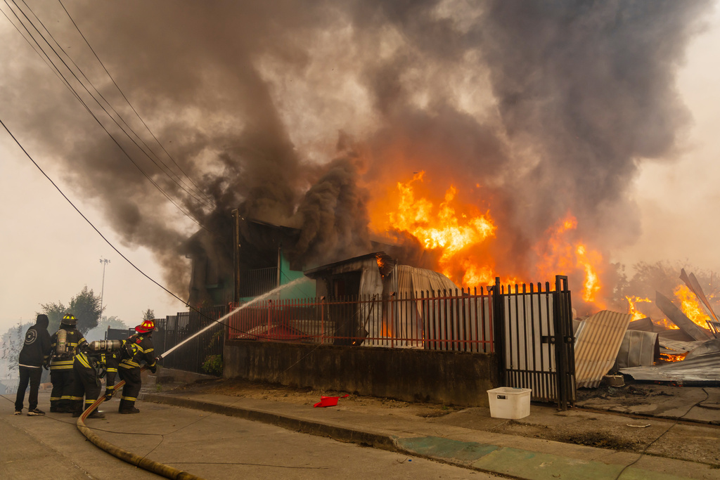 Firefighters battle a blaze at a house as wildfires burn in Lirquen, Chile, Sunday, Jan. 18, 2026. (AP Photo/Javier Torres)