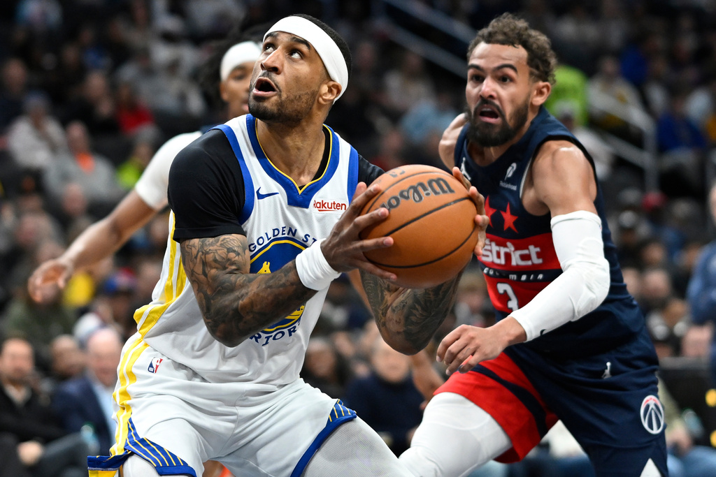 Golden State Warriors guard Gary Payton II, left, goes to shoot against Washington Wizards guard Trae Young during the first half of an NBA basketball game, Monday, March 16, 2026, in Washington. (AP Photo/John McDonnell)