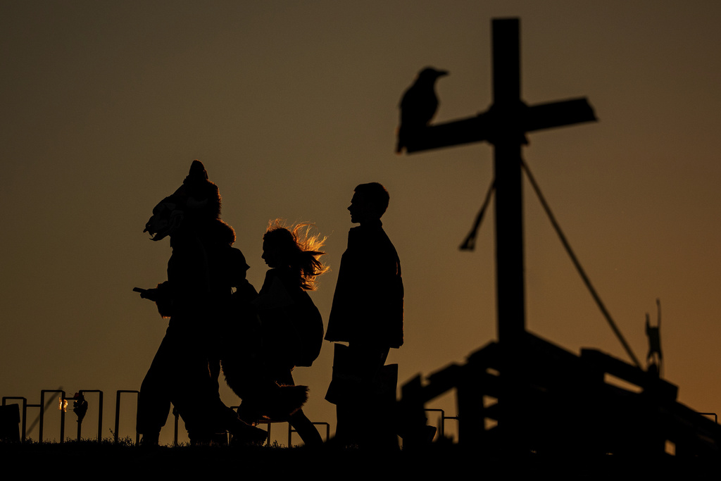 People wearing costumes are silhouetted against the sunset sky at the West Side Hallo Fest, the country's largest Halloween festival in Bucharest, Romania, Friday, Oct. 24, 2025. (AP Photo/Andreea Alexandru)