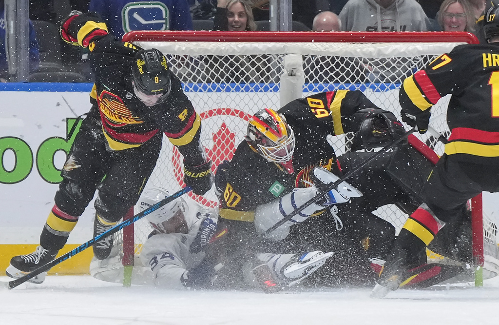Toronto Maple Leafs' Auston Matthews (34) crashes into Vancouver Canucks goalie Nikita Tolopilo (60) after being taken down by Conor Garland (8) during overtime of an NHL hockey game, in Vancouver, on Saturday, Jan. 31, 2026. (Darryl Dyck/The Canadian Press via AP)