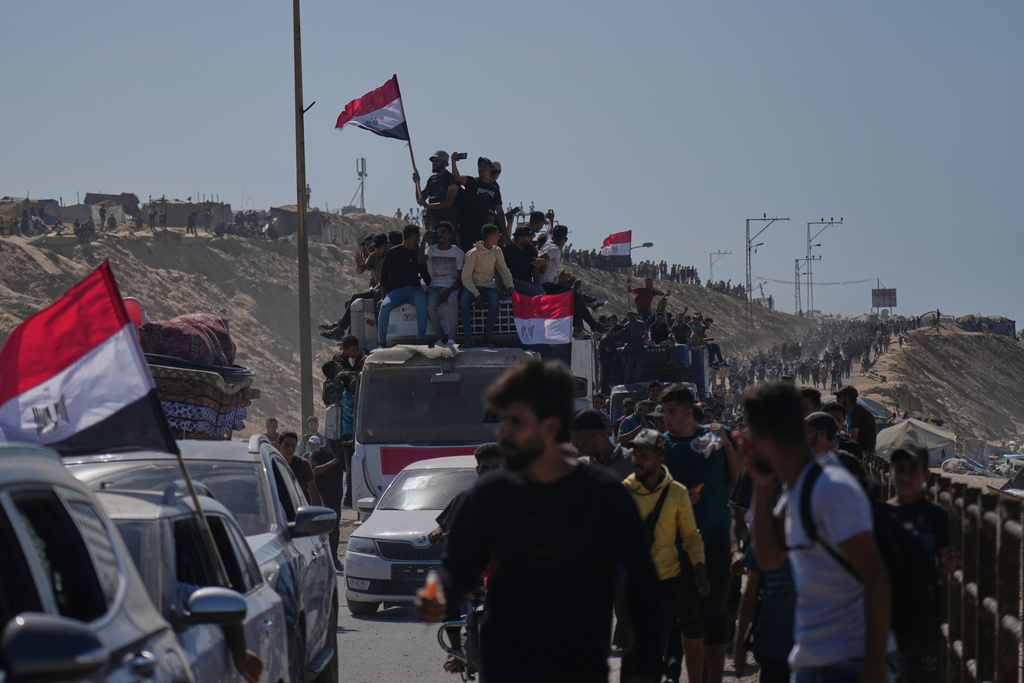Displaced Palestinians ride on vehicles and wave Egyptian flags as they move along the coastal road near Wadi Gaza in the central Gaza Strip, heading toward Gaza City, Friday, Oct. 10, 2025, after Israel and Hamas agreed to a pause in their war and the release of the remaining hostages. (AP Photo/Abdel Kareem Hana)