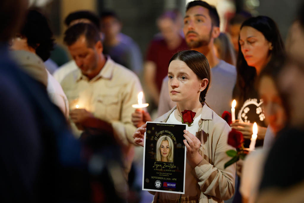 Community members hold flyers and candles as they gather for a vigil honoring the life of Iryna Zarutska, who was fatally stabbed on a commuter train last month, Monday, Sept. 22, 2025, in Charlotte, N.C. (AP Photo/Nell Redmond)