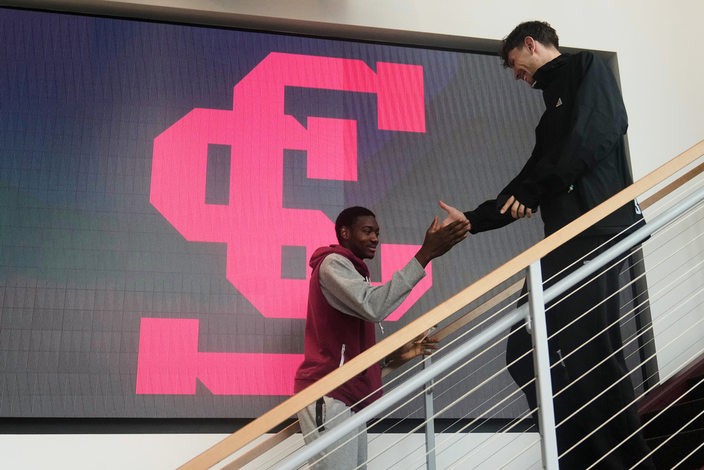 Santa Clara basketball player Thierry Darlan, left, greets teammate Jake Ensminger while walking toward study hall during an interview at the Santa Clara University campus in Santa Clara, Calif., Thursday, Nov. 13, 2025. (AP Photo/Jeff Chiu)