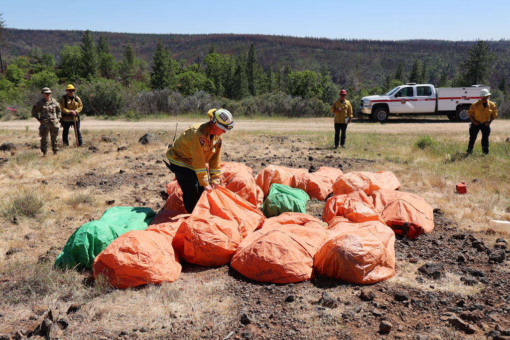 This image provided by Cal Fire shows firefighters practicing deployment of fire shelters used for training during an exercise in Paynes Creek, Calif., on May 6, 2025. (Cal Fire via AP)