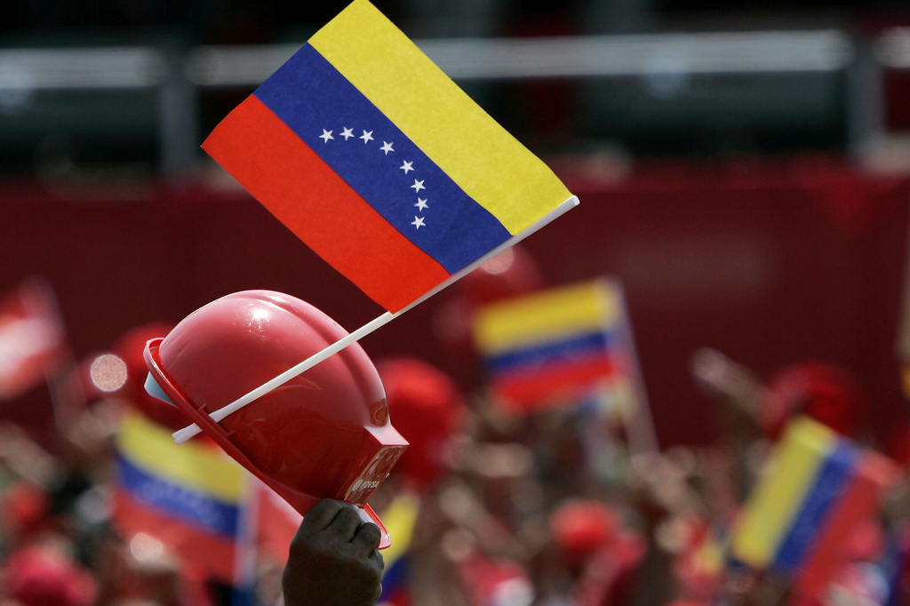 FILE - Venezuelan oil workers wave their helmets and national flags as President Hugo Chavez, unseen, delivers a speech at Jose Antonio Anzoategui oil complex in Barcelona, Venezuela, Tuesday, May 1, 2007. (AP Photo/Fernando Llano, File)