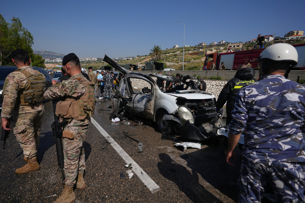 Security forces and emergency responders gather around a damaged vehicle at the scene of an Israeli airstrike that hit a car in the coastal town of Saadiyat, south of Beirut, Lebanon, Saturday, May 9, 2026. (AP Photo/Hassan Ammar)