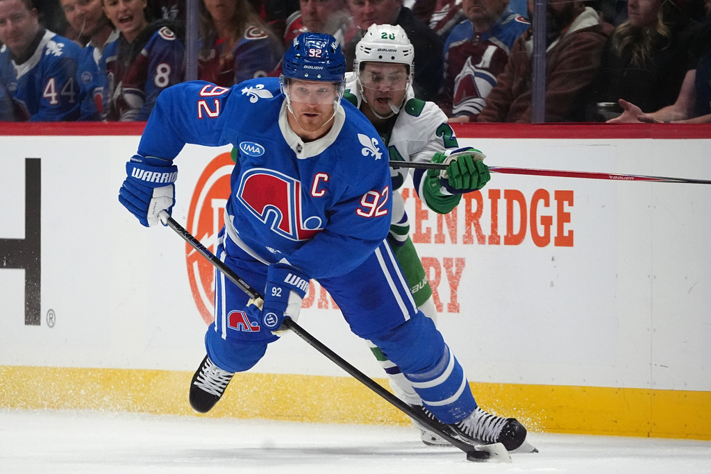 Colorado Avalanche left wing Gabriel Landeskog, front, collects the puck as Carolina Hurricanes center Sebastian Aho defends in the second period of an NHL hockey game Thursday, Oct. 23, 2025, in Denver. (AP Photo/David Zalubowski)