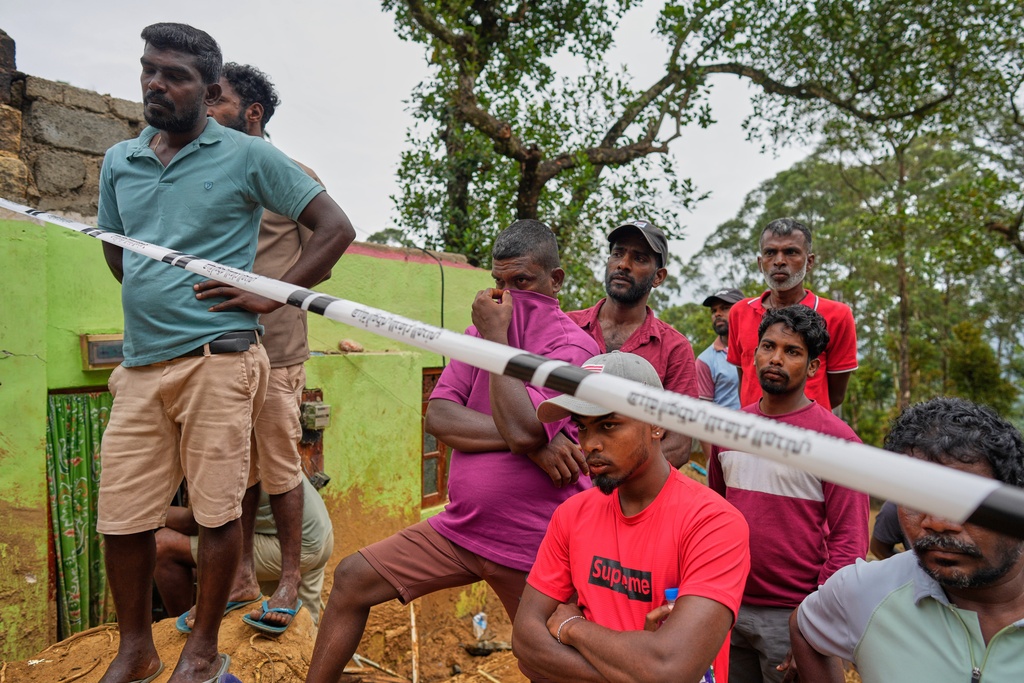 Family members and relatives of tea plantation workers watch rescuers try to dig out a buried body after a landslide following Cyclone Ditwah at Craighead Estate in Nawalapitiya, Sri Lanka, Thursday, Dec. 11, 2025. (AP Photo/Eranga Jayawardena)