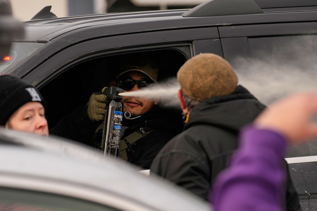 A federal immigration officer deploys pepper spray as officers make an arrest Sunday, Jan. 11, 2026, in Minneapolis. (AP Photo/John Locher)