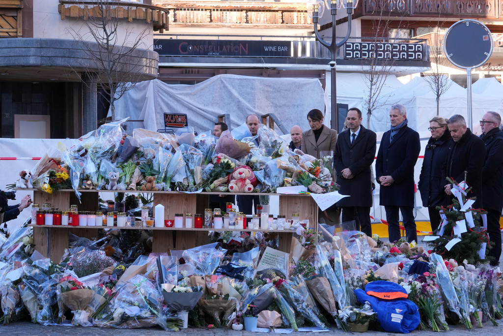 Swiss Minister of Justice Beat Jans and State Councillor Mathias Reynard lay flowers at the sealed off Le Constellation bar in Crans-Montana, Swiss Alps, Switzerland, Saturday, Jan. 3, 2026, where a devastating fire left dead and injured during the New Year's celebrations. (AP Photo/Antonio Calanni)