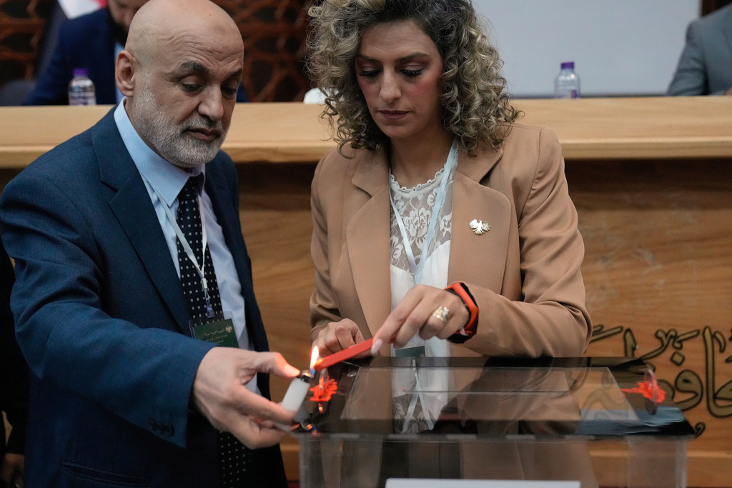 Syrian election officials burn red wax to stamp a ballot box ahead of the parliamentary elections at Latakia's Governor ballot station, in the coastal city of Latakia, Syria, Sunday, Oct. 5, 2025. (AP Photo/Hussein Malla)