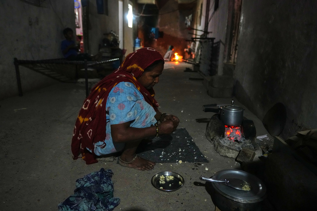 A migrant woman prepares a meal using coal at a deserted ceramic workers' quarters in Morbi, in the Indian state of Gujarat, Wednesday, April 8, 2026. (AP Photo/Ajit Solanki)