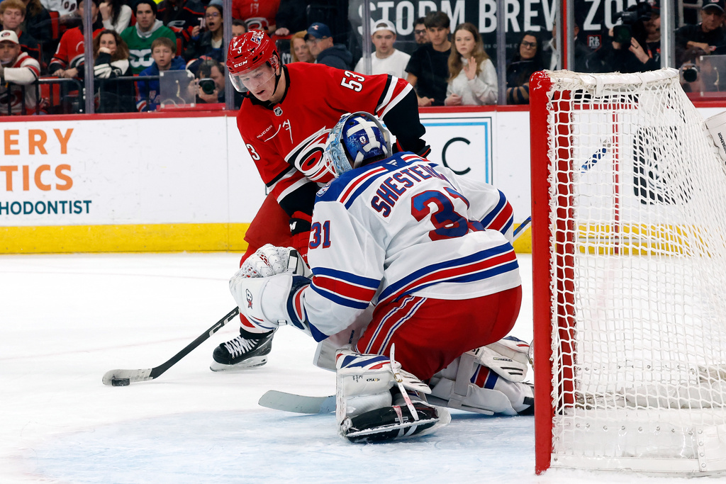 Carolina Hurricanes' Jackson Blake (53) controls the puck in front of New York Rangers goaltender Igor Shesterkin (31) during an overtime period of an NHL hockey game in Raleigh, N.C., Monday, Dec. 29, 2025. (AP Photo/Karl DeBlaker)