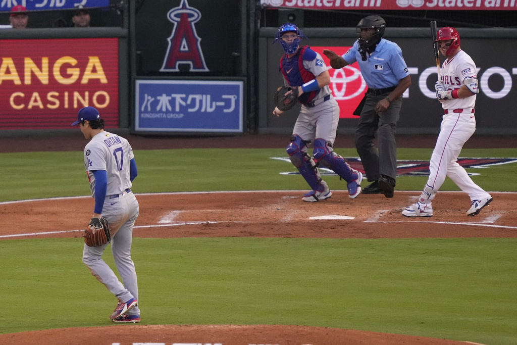 Los Angeles Angels' Mike Trout, right, smiles after Los Angeles Dodgers starting pitcher Shohei Ohtani after Ohtani struck him out while catcher Will Smith stands at the plate during the first inning of a baseball game Wednesday, Aug. 13, 2025, in Anaheim, Calif. (AP Photo/Mark J. Terrill)