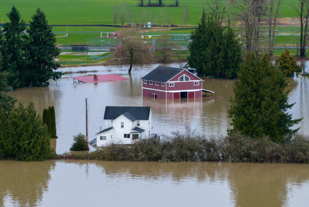 A n aerial view of a home and a barn surrounded by floodwaters in Snohomish, Wash., Thursday, Dec. 11, 2025. (AP Photo/Stephen Brashear)