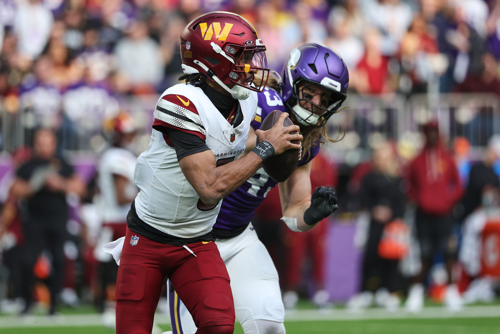 Washington Commanders quarterback Jayden Daniels (5) looks to pass while being chased by Minnesota Vikings linebacker Andrew Van Ginkel (43) during the first half of an NFL football game, Sunday, Dec. 7, 2025, in Minneapolis. (AP Photo/Matt Krohn)
