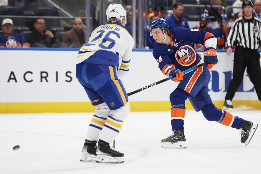 New York Islanders center Calum Ritchie (64) passes the puck around Buffalo Sabres defenseman Rasmus Dahlin (26) during the second period of an NHL hockey game, Saturday, Jan. 24, 2026, in Elmont, N.Y. (AP Photo/Heather Khalifa)