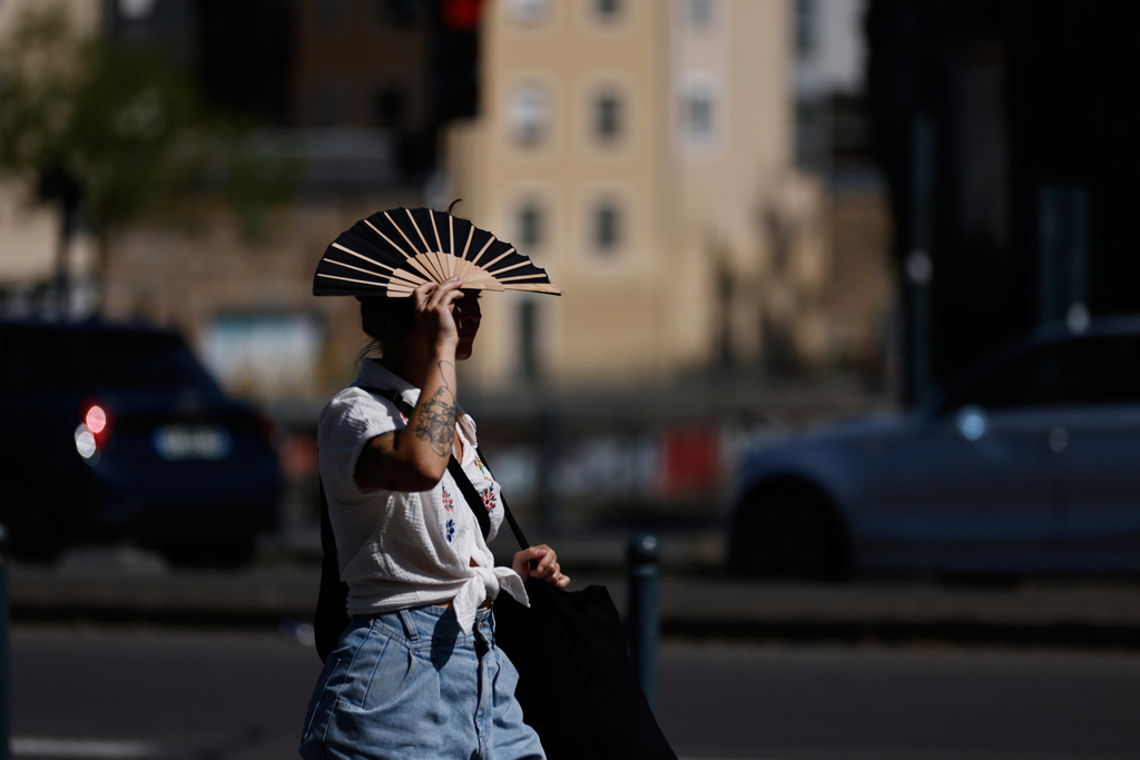 A woman shields herself from the sun with a fan in Rennes, western France, Monday, June 22, 2026. (AP Photo/Jeremias Gonzalez)