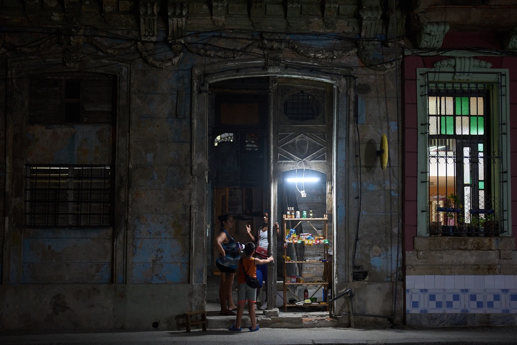 A vendor speaks with customers in the doorway of his building in Havana, Thursday, March 5, 2026. (AP Photo/Ramon Espinosa)