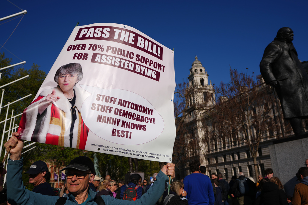 A campaigner holds a banner outside parliament in London as a proposed law to legalise assisted dying in England and Wales will run out of time on Friday, more than a year after MPs first voted in favour of it, Friday, April 24, 2026. (AP Photo/Kirsty Wigglesworth)