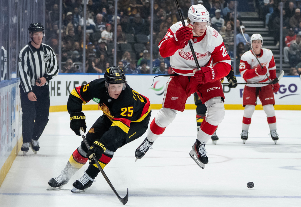 Detroit Red Wings' Nate Danielson (29) jumps to avoid Vancouver Canucks' Elias Pettersson (25) as they vie for the puck during first period NHL hockey action in Vancouver, B.C., Monday, Dec. 8, 2025. (Ethan Cairns/The Canadian Press via AP)