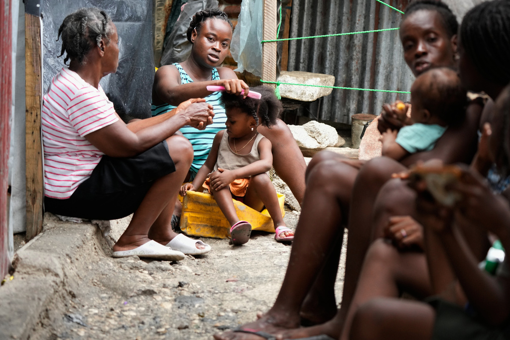 Kettia Jean Charles combs her niece's hair at the Ministry of Public Works, Transport and Communications office, which was converted into a shelter for people displaced by gang violence in Port-au-Prince, Haiti, Wednesday, Sept. 24, 2025. (AP Photo/Odelyn Joseph)