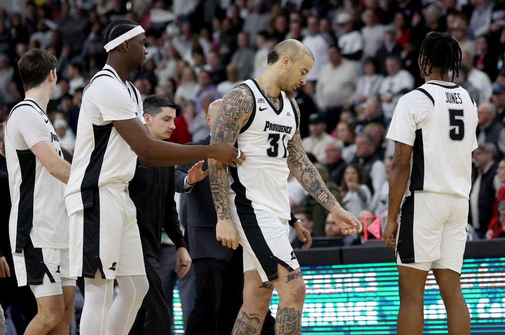Providence forward Duncan Powell (31) is escorted off the court after getting ejected following a fight during the second half of an NCAA college basketball game against St. John's, Saturday, Feb. 14, 2026, in Providence, R.I. (AP Photo/Mark Stockwell)