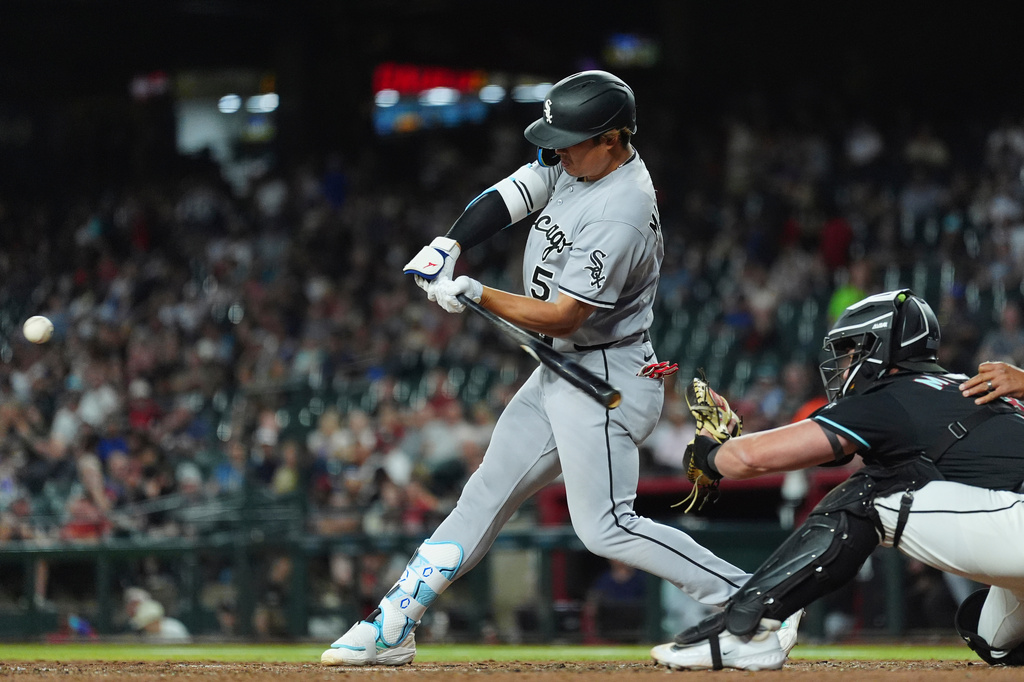 Chicago White Sox's Munetaka Murakami (5) starts his swing on a single as Arizona Diamondbacks catcher James McCann reaches for the ball during the fifth inning of a baseball game, Wednesday, April 22, 2026, in Phoenix. (AP Photo/Ross D. Franklin)