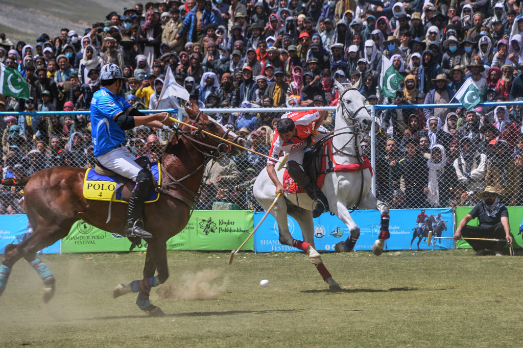 Players of Chitral region team, in red, and Gilgit-Baltistan region team, in blue, battle for the ball during the final match of the three-day annual Shandur Polo Festival in Shandur Pass, in the Ghizer district of Gilgit-Baltistan, northern Pakistan, Saturday, June 13, 2026. (AP Photo/Zubair Abbasi)