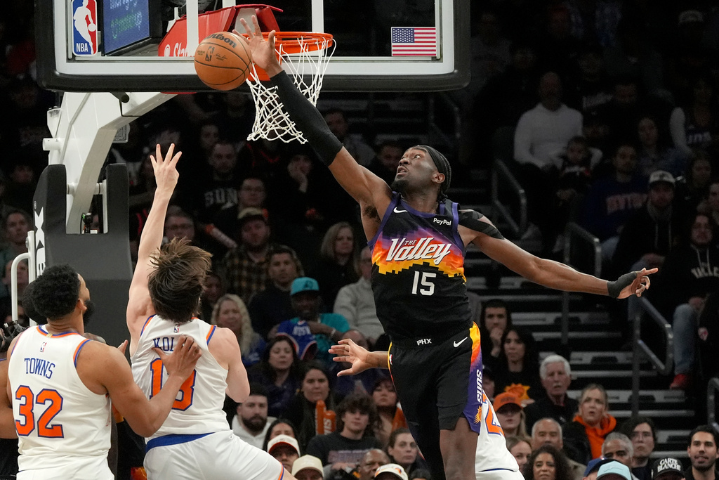Phoenix Suns center Mark Williams (15) blocks a shot by New York Knicks guard Tyler Kolek as Knicks center Karl-Anthony Towns (32) looks on during the second half of an NBA basketball game, Friday, Jan. 9, 2026, in Phoenix. (AP Photo/Ross D. Franklin)