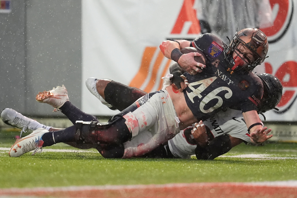 Navy fullback Alex Tecza (46) gains a first down as he tackled by Cincinnati safety Antwan Peek Jr., behind, during the first half of the Liberty Bowl NCAA college football game Friday, Jan. 2, 2026, in Memphis, Tenn. (AP Photo/George Walker IV)