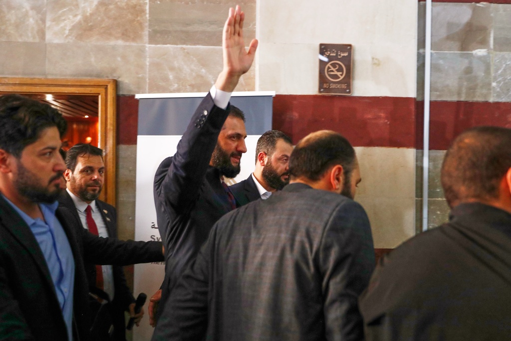Syrian interim President Ahmad al-Sharaa waves as he enters a polling station where electoral college members are voting in a parliamentary election in Damascus, Syria, Sunday, Oct. 5, 2025. (AP Photo/Omar Sanadiki)