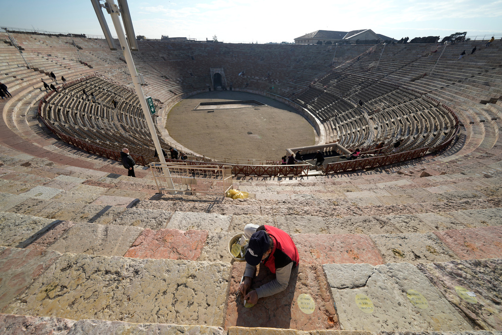 A worker removes seat number stickers used to mark places during concerts at the Arena of Verona, Italy, Wednesday, Dec. 10, 2025. (AP Photo/Luca Bruno)