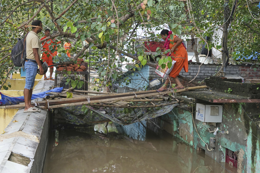 Bindu Pandey, 40, right, leaves her flooded house to a temporary shelter in New Delhi, India, Friday, Sept. 5, 2025. (AP Photo/Manish Swarup)