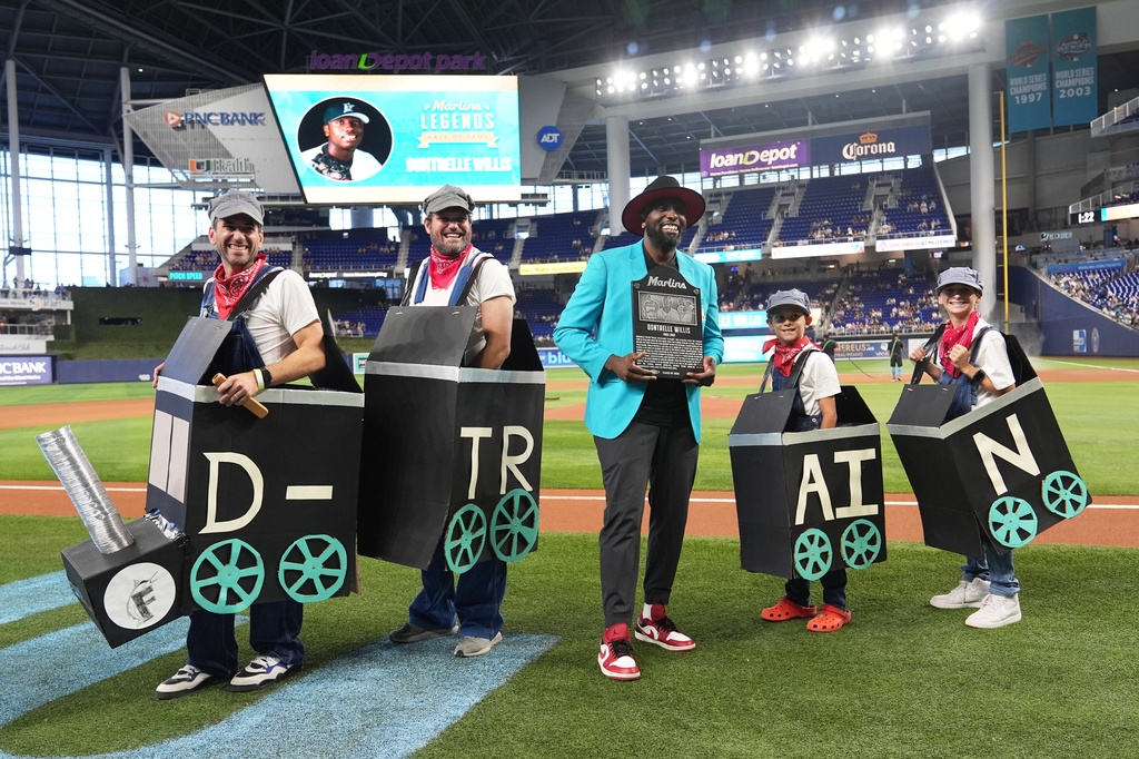 Former Miami Marlins pitcher Dontrelle Willis, center, poses with people dressed as the D-Train before being inducted into the Marlins Legends Hall of Fame before baseball game between the Miami Marlins and the Los Angeles Dodgers, Sunday, Sept. 13, 2026, in Miami. (AP Photo/Lynne Sladky)
