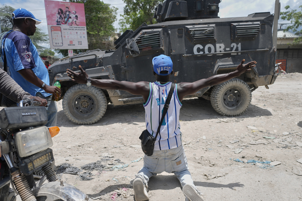 FILE - A resident of Cité Soleil kneels before a police armored vehicle and demands that the police go and fight the gangs that control their neighborhood, in Port-au-Prince, Haiti, May 12, 2026. (AP Photo/Odelyn Joseph, File)
