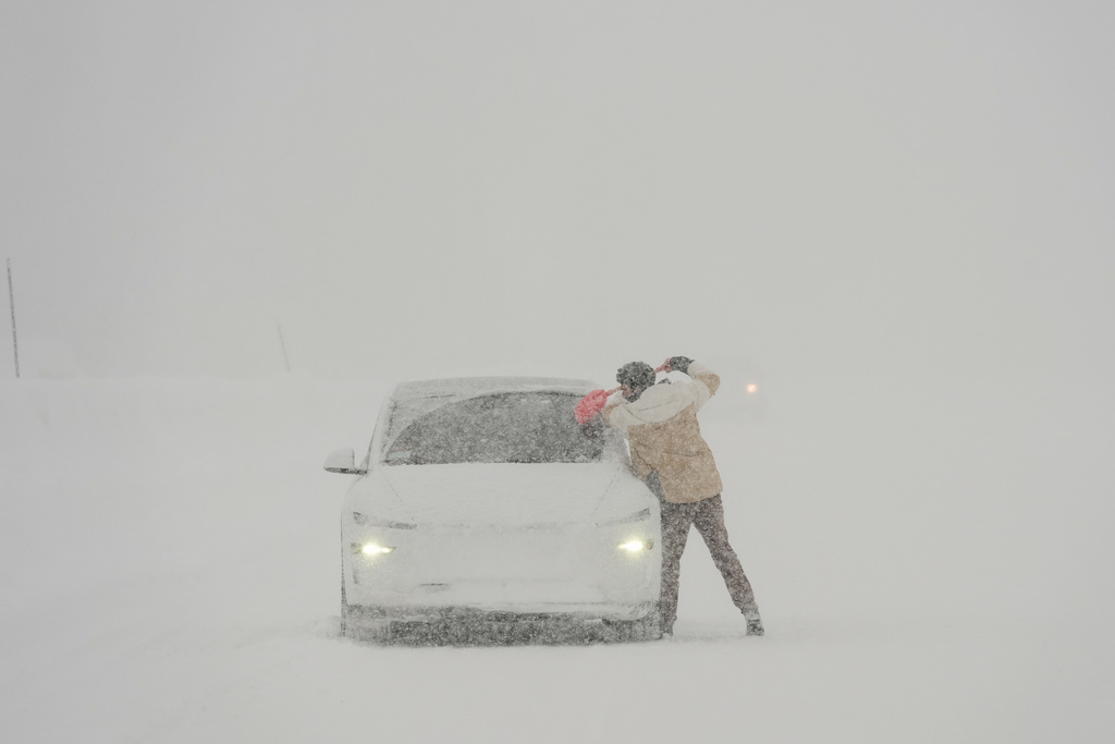 A motorist scrapes ice off his vehicle along interstate 80 during a snow storm Thursday, Feb. 19, 2026, near Camp Spaulding in Placer County, Calif. (AP Photo/Godofredo A. Vásquez)