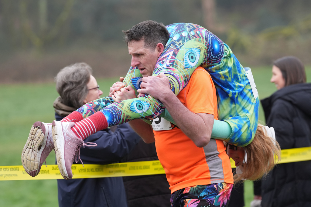 People take part in the annual UK Wife Carrying Race in Dorking, England, Sunday March 8, 2026. (Gareth Fuller/PA via AP)