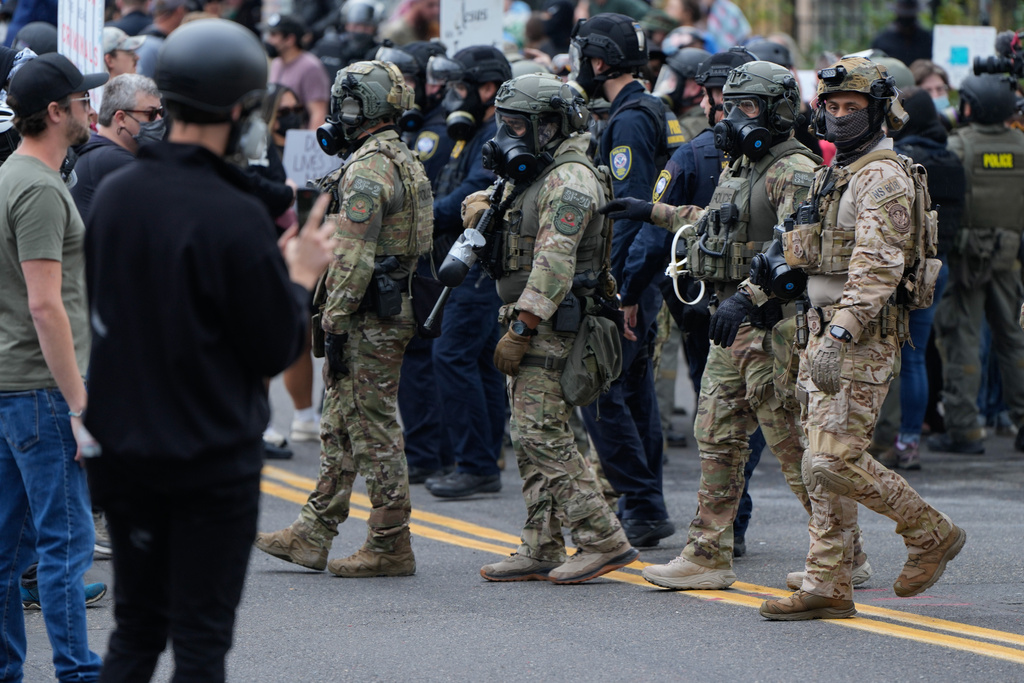 Law enforcement officers move towards protesters to make a path for a vehicle to leave a U.S. Immigration and Customs Enforcement facility on Saturday, Oct. 4, 2025, in Portland, Ore. (AP Photo/Jenny Kane)
