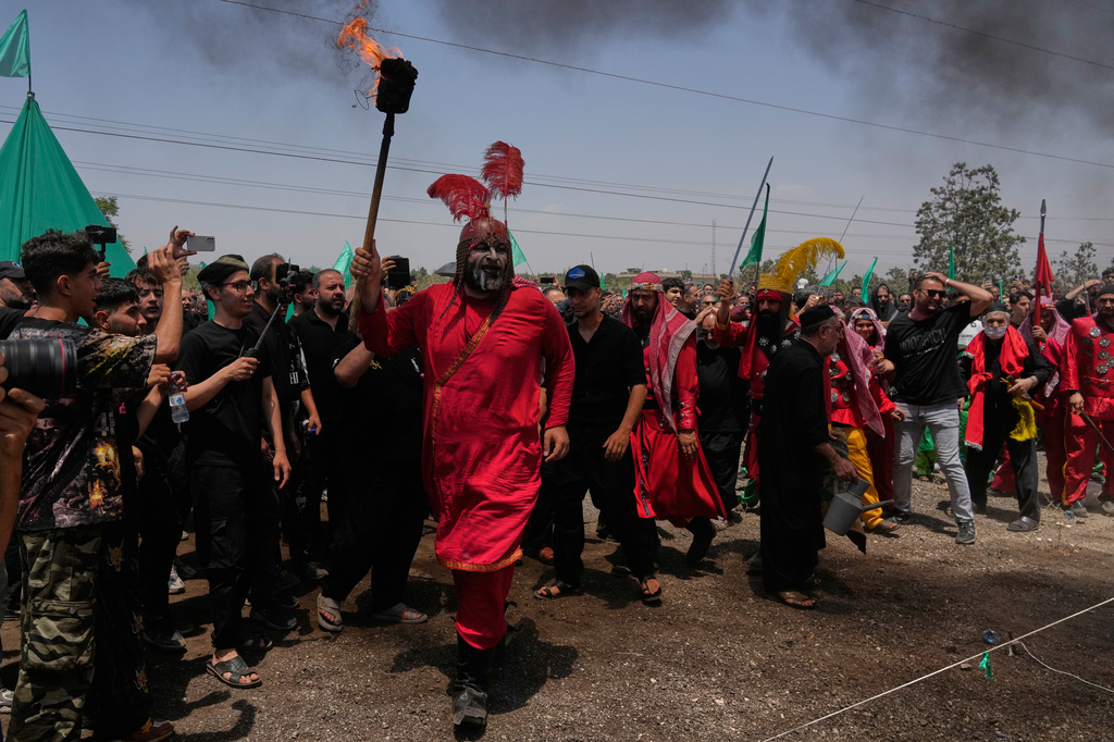 A man carries a torch in Tehran, Iran, Thursday, June 25, 2026, while re-enacting the enemy of Imam Hussein in the battle of Karbala in A.D. 680 in present-day Iraq, in which the Imam, a grandson of the Prophet Muhammad, one of Shiite Islam's most beloved saints, and his family and companions were killed after refusing to pledge allegiance to the Umayyad caliphate. (AP Photo/Vahid Salemi)