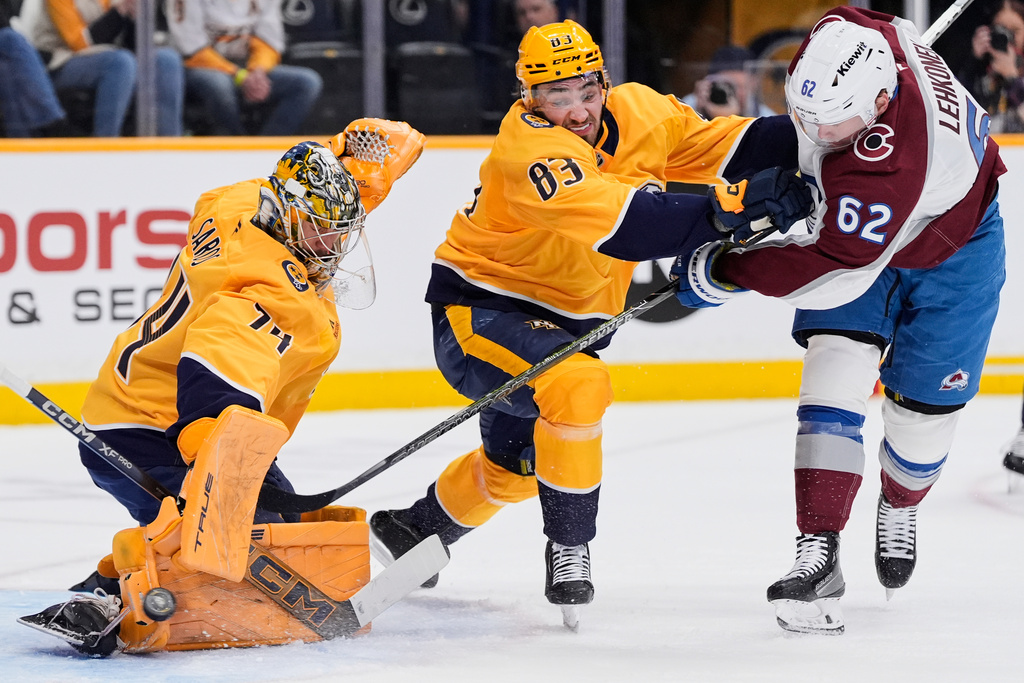 Colorado Avalanche left wing Artturi Lehkonen (62) scores a goal past Nashville Predators goaltender Juuse Saros (74) and defenseman Adam Wilsby (83) during the first period of an NHL hockey game Tuesday, Dec. 9, 2025, in Nashville, Tenn. (AP Photo/George Walker IV)